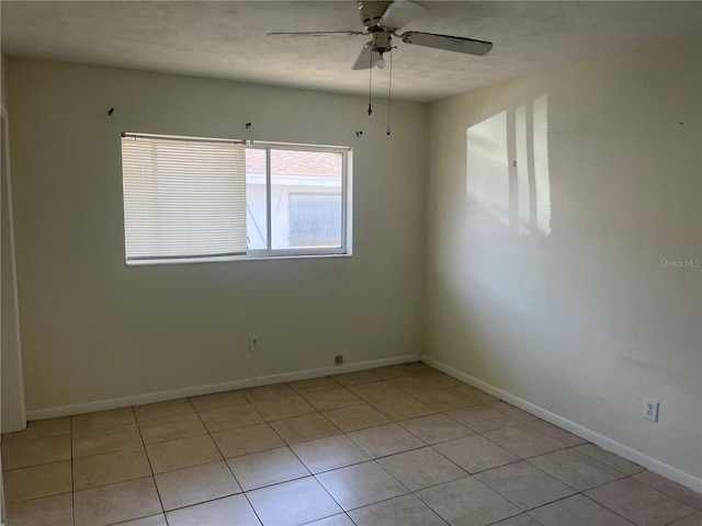 spare room featuring ceiling fan, baseboards, and light tile patterned floors