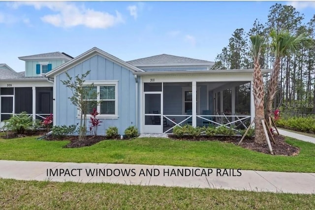 back of property featuring a sunroom, board and batten siding, and a lawn