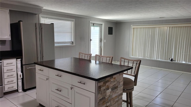 1066 5th St, Okeechobee, FL 34974 - kitchen with freestanding refrigerator, dark countertops, light tile patterned floors, and a kitchen breakfast bar