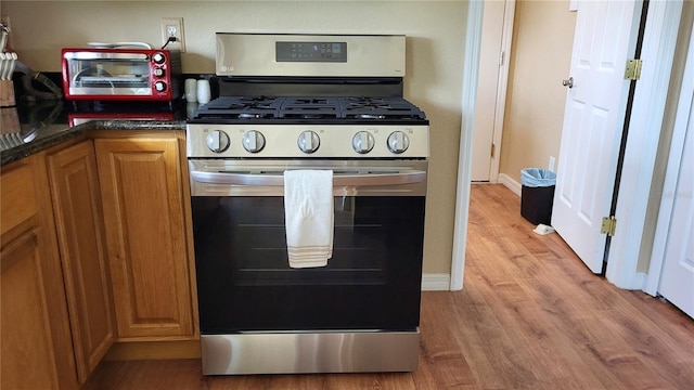 16159 NW 258th St, Okeechobee, FL 34972 - kitchen featuring gas range, light wood-style floors, brown cabinetry, and baseboards