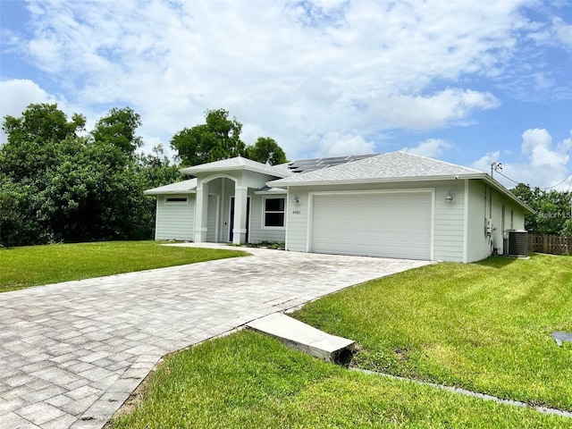 4486 SW Cacao St, Port St Lucie, FL 34953 - single story home featuring central air condition unit, roof mounted solar panels, a garage, a front lawn, and decorative driveway
