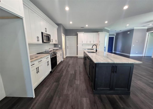 4486 SW Cacao St, Port St Lucie, FL 34953 - kitchen with appliances with stainless steel finishes, white cabinets, dark wood-type flooring, recessed lighting, and a kitchen island with sink