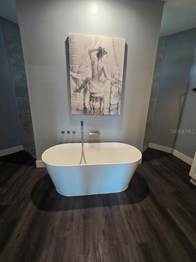 4486 SW Cacao St, Port St Lucie, FL 34953 - bathroom featuring wood finished floors, a freestanding tub, and baseboards