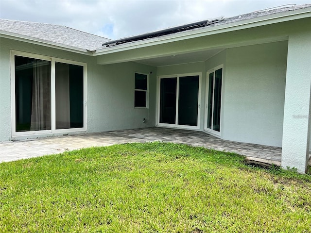 4486 SW Cacao St, Port St Lucie, FL 34953 - back of property with stucco siding, a patio, a lawn, and a shingled roof