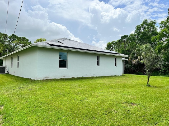 4486 SW Cacao St, Port St Lucie, FL 34953 - view of property exterior featuring stucco siding, solar panels, and a yard