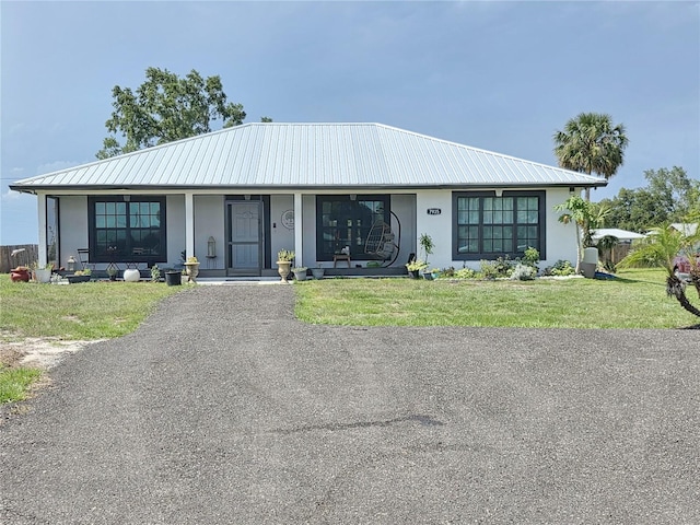 7935 NW 90th Ct, Okeechobee, FL 34972 - view of front of home featuring stucco siding, metal roof, a front yard, and covered porch