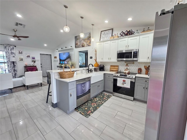 7935 NW 90th Ct, Okeechobee, FL 34972 - kitchen featuring stainless steel appliances, gray cabinets, a sink, open floor plan, and a peninsula