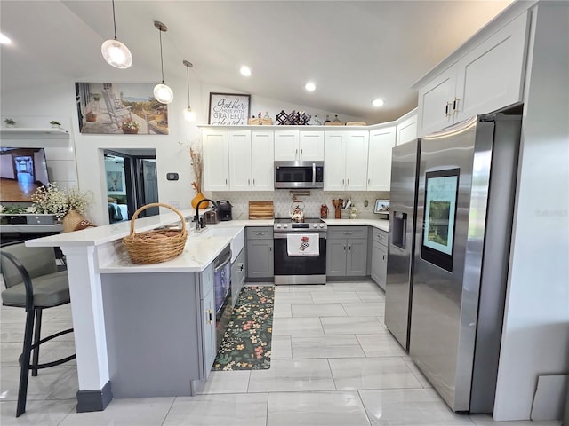 7935 NW 90th Ct, Okeechobee, FL 34972 - kitchen with stainless steel appliances, gray cabinets, lofted ceiling, tasteful backsplash, and light countertops
