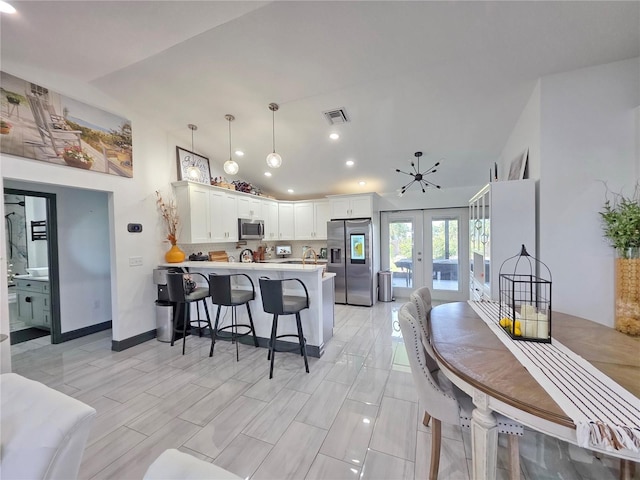 7935 NW 90th Ct, Okeechobee, FL 34972 - kitchen featuring appliances with stainless steel finishes, a peninsula, french doors, a kitchen breakfast bar, and light countertops