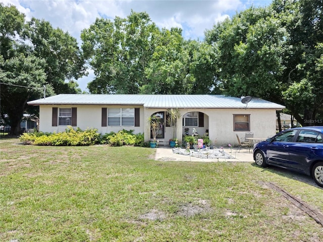 7740 NW 81st Ct, Okeechobee, FL 34972 - ranch-style home with stucco siding, a front lawn, and metal roof