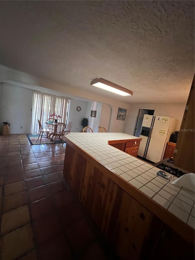 1096 8th St, Okeechobee, FL 34974 - kitchen featuring tile countertops, white refrigerator with ice dispenser, and a textured ceiling