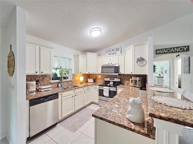 3897 NW 22nd Ave, Okeechobee, FL 34972 - kitchen featuring appliances with stainless steel finishes, a sink, vaulted ceiling, backsplash, and a peninsula
