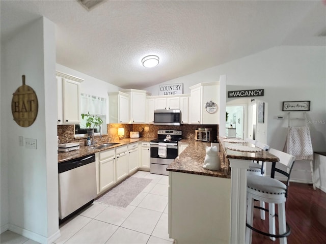 3897 NW 22nd Ave, Okeechobee, FL 34972 - kitchen with stainless steel appliances, a peninsula, lofted ceiling, backsplash, and a kitchen breakfast bar
