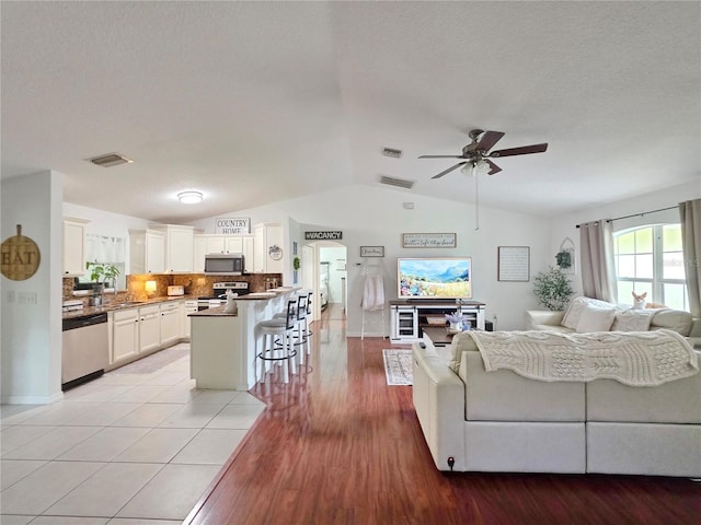 3897 NW 22nd Ave, Okeechobee, FL 34972 - living area featuring vaulted ceiling, a ceiling fan, light wood-style flooring, and baseboards