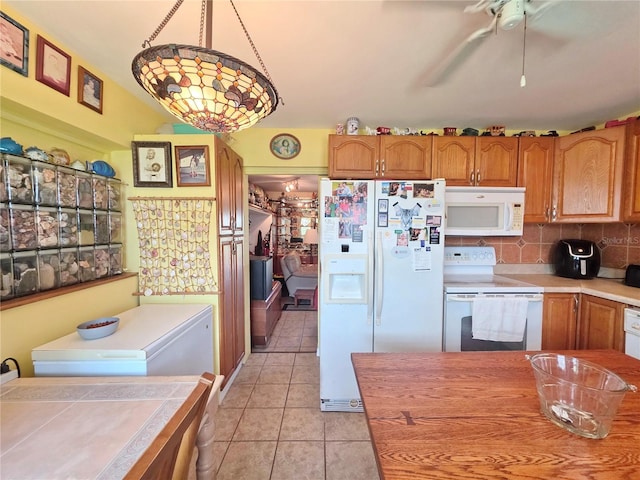 1209 5th St, Okeechobee, FL 34974 - kitchen featuring white appliances, light tile patterned floors, light countertops, brown cabinets, and decorative backsplash