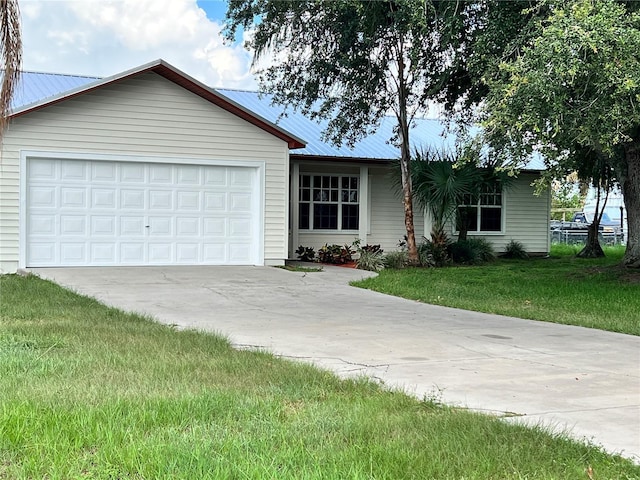 1150 SW 83rd Ave, Okeechobee, FL 34974 - ranch-style house with driveway, a metal roof, a front lawn, and a garage