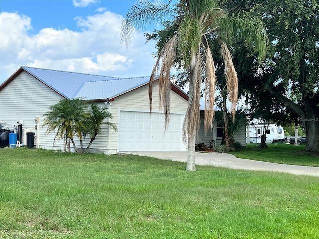 1150 SW 83rd Ave, Okeechobee, FL 34974 - view of side of property featuring concrete driveway, a garage, a yard, and a metal roof