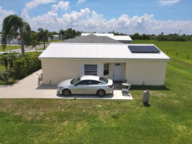 1000 SW 44th Blvd, Okeechobee, FL 34974 - back of property with stucco siding, a lawn, solar panels, and a metal roof