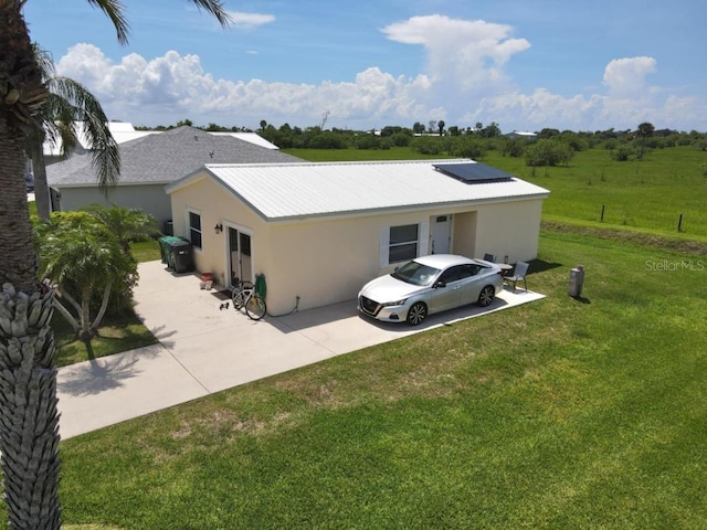 1000 SW 44th Blvd, Okeechobee, FL 34974 - rear view of property featuring stucco siding, a yard, driveway, solar panels, and a metal roof