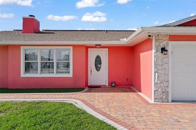 402 SW Seaflower Ter, Port St Lucie, FL 34984 - entrance to property featuring stucco siding, a chimney, roof with shingles, and a garage