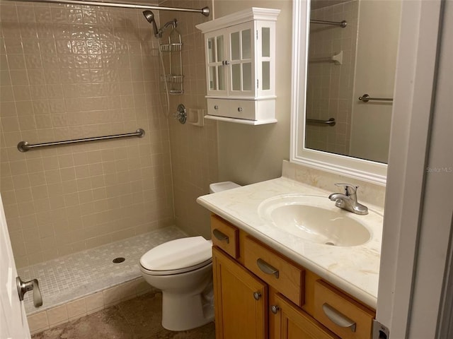 bathroom with toilet, vanity, tiled shower, and tile flooring