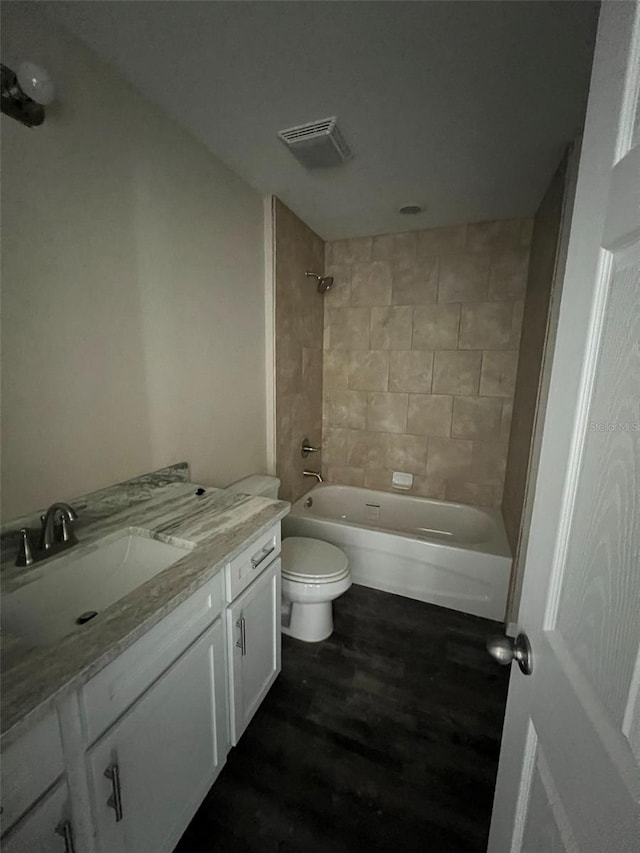 full bathroom featuring tiled shower / bath combo, toilet, vanity, and wood-type flooring