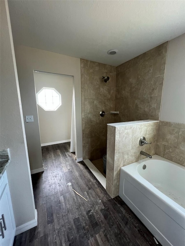 bathroom featuring a textured ceiling, tiled shower, vanity, and wood-type flooring