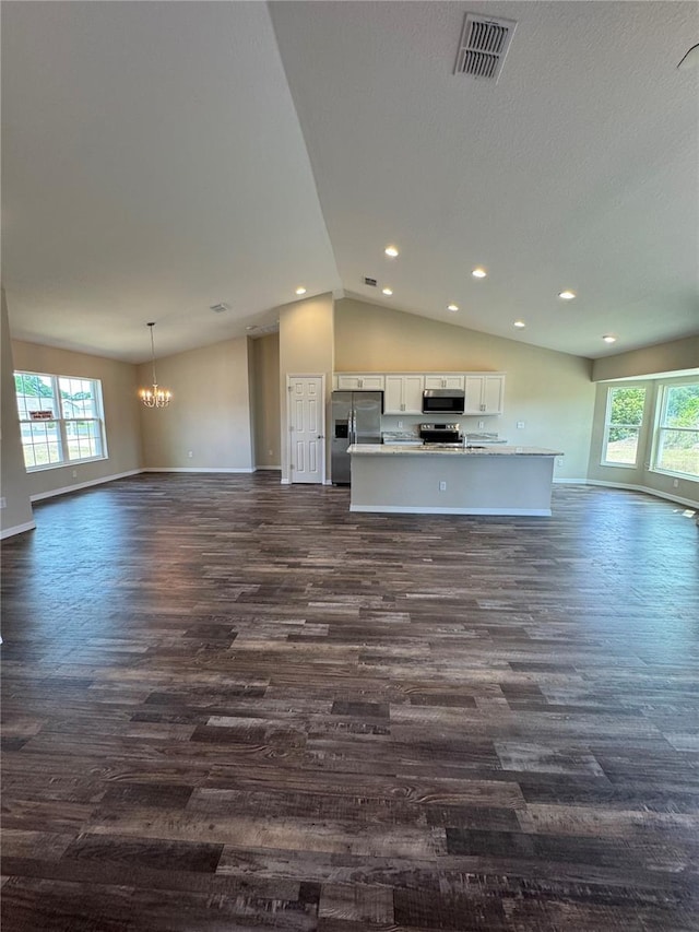 6711 SW 64th Ave, Ocala, FL 34476 - unfurnished living room featuring dark wood-type flooring, vaulted ceiling, visible vents, and an inviting chandelier