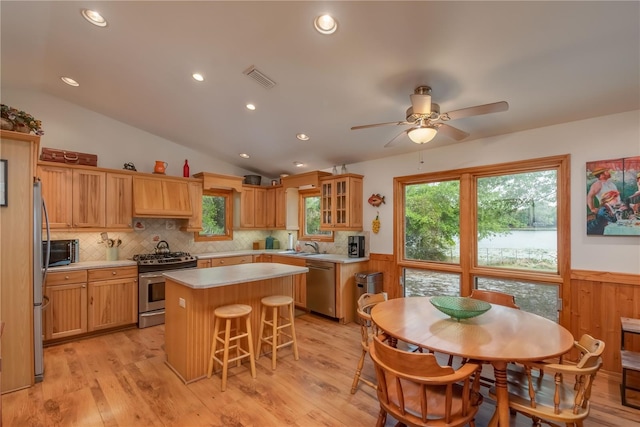 kitchen with stainless steel appliances, a kitchen island, ceiling fan, tasteful backsplash, and lofted ceiling