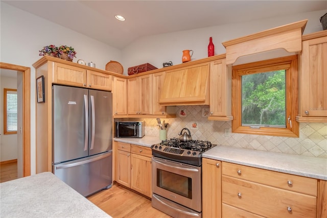 kitchen featuring backsplash, custom exhaust hood, light hardwood / wood-style flooring, and appliances with stainless steel finishes