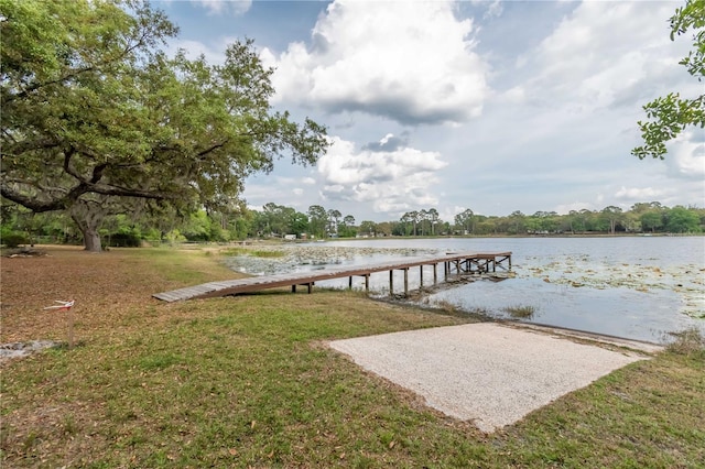 view of dock with a water view and a lawn