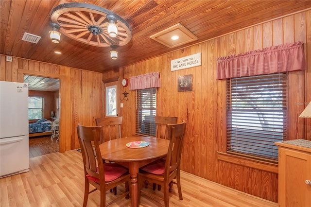 dining room with wood walls, wooden ceiling, light hardwood / wood-style floors, and a wealth of natural light