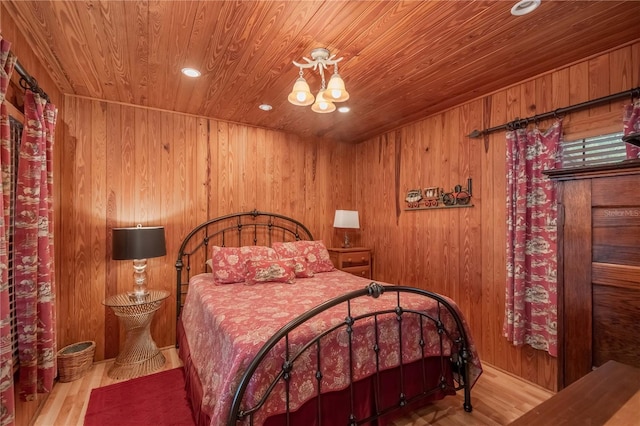 bedroom with an inviting chandelier, light hardwood / wood-style floors, wood ceiling, and wooden walls