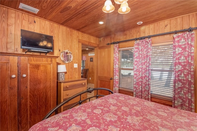 bedroom with an inviting chandelier, wooden walls, and wood ceiling