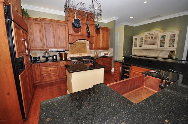 kitchen featuring backsplash, an island with sink, beverage cooler, stove, and dark hardwood / wood-style flooring