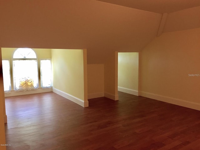 empty room with vaulted ceiling and dark hardwood / wood-style floors