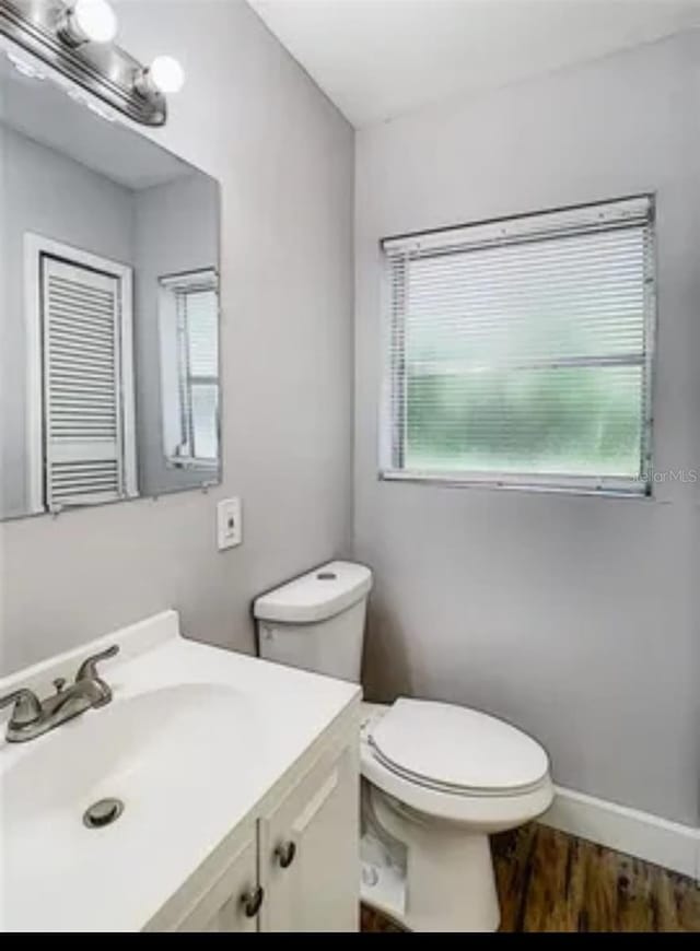 bathroom with toilet, vanity, and wood-type flooring