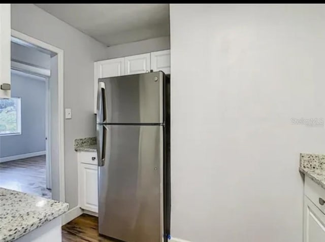 kitchen featuring white cabinetry, light stone counters, stainless steel fridge, and dark hardwood / wood-style flooring