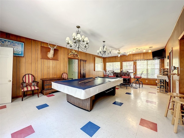 rec room with ceiling fan with notable chandelier, wood walls, light tile floors, and billiards