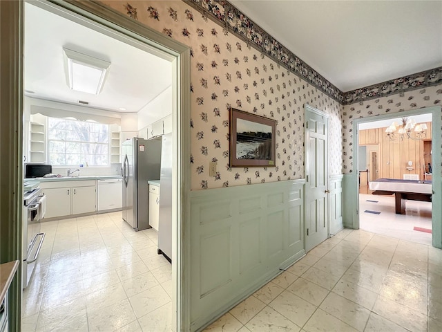 hall featuring a notable chandelier, light tile floors, and sink