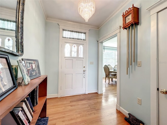 entrance foyer featuring an inviting chandelier, crown molding, and light wood-type flooring