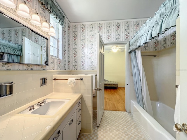 bathroom featuring hardwood / wood-style floors, shower / tub combo with curtain, ceiling fan, tile walls, and vanity with extensive cabinet space