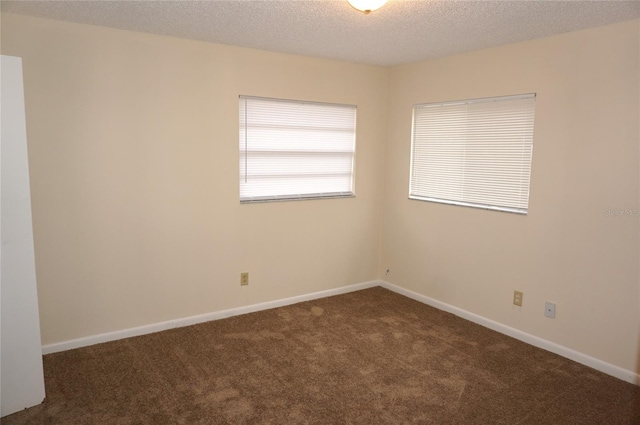 spare room with dark carpet and a textured ceiling