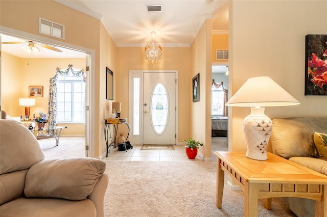 foyer with crown molding, light colored carpet, and ceiling fan with notable chandelier