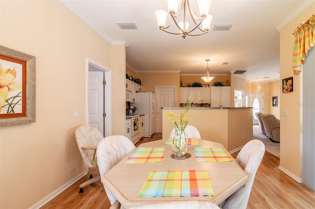 dining area with crown molding, light hardwood / wood-style floors, and a chandelier