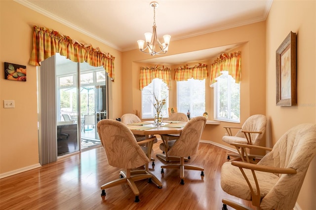 dining space with a chandelier, crown molding, and light hardwood / wood-style flooring