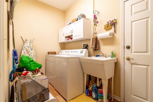 washroom featuring hookup for a washing machine, cabinets, washing machine and dryer, and light wood-type flooring