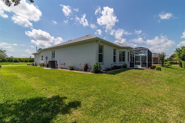 view of side of property with a yard, central air condition unit, and a lanai