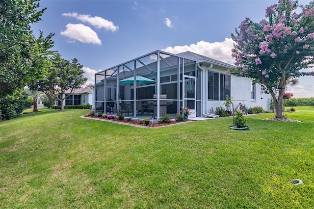 rear view of property with a lanai and a lawn