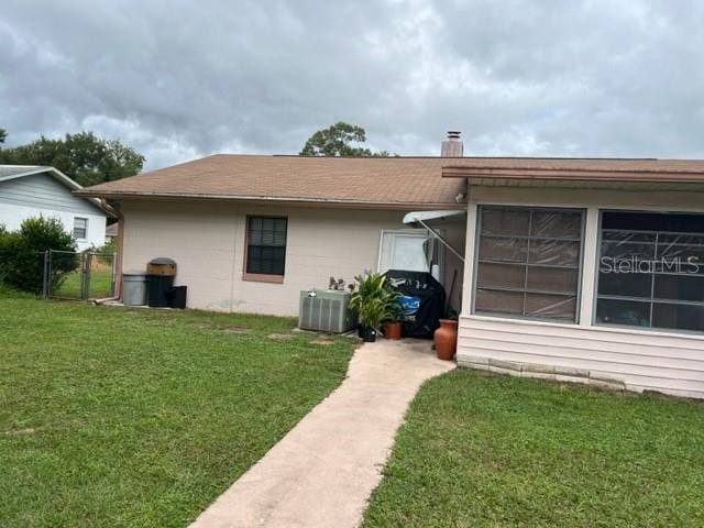 back of property with a lawn and central AC